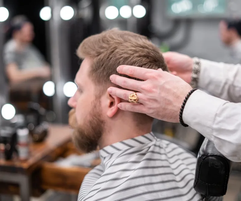 Cliente recibiendo un corte cuidado por un profesional en una barbería luminosa